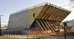 Vue du chantier. La structure en bois de la salle apparaît, soutenue par les troncs qui formeront le foyer.